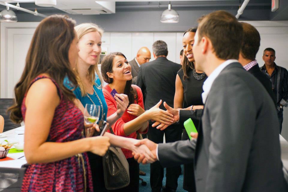 Image of several professionals meeting at an event shaking hands and networking.