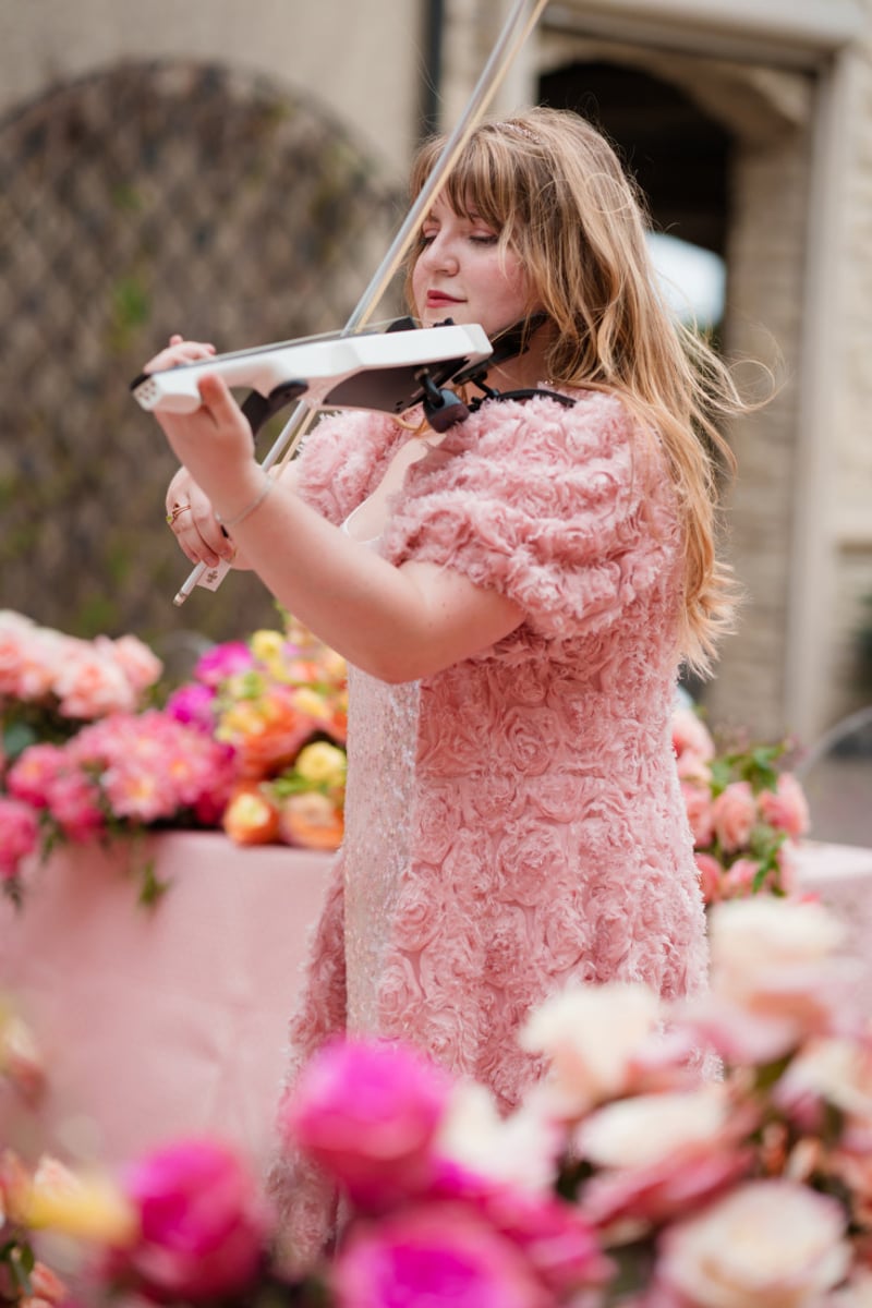 Ana Done performing electric violin among pink wedding florals